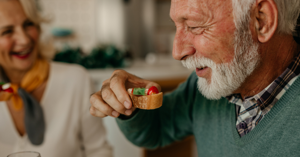 A softly lit holiday scene featuring an aging parent and adult child sharing a quiet, warm moment at home. Light holiday décor is visible in the background, symbolizing the emotions and realizations that often arise during December gatherings when families notice changing needs in their loved ones.